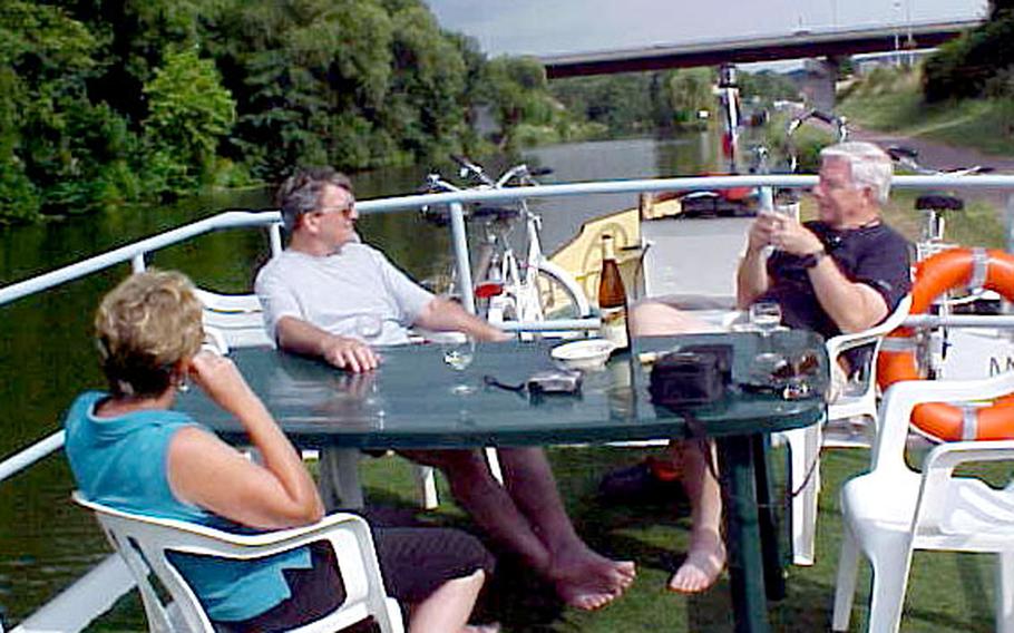 Former Army stairwell neighbors, Arlene and Glenn Walker, left, chat with Ingram Philips on the Johanna. In the background are bicycles furnished on board for day trips along the old towpath and for visiting nearby French villages.