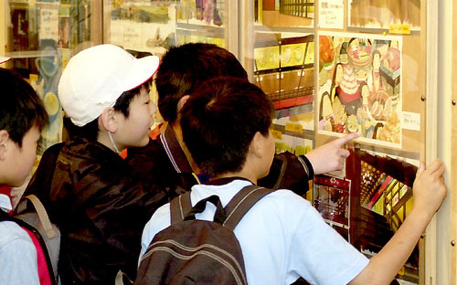 Japanese schoolboys on a day trip to the museum look at the many drawings and animation cells used in the movie "Spirited Away."