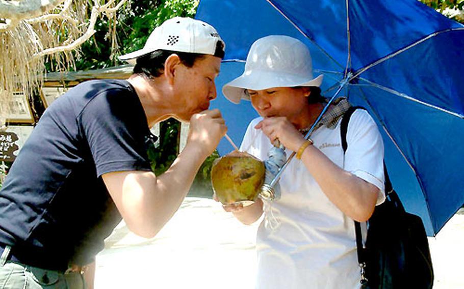 Masaki Kawato and his wife, Masako, tourists from Tokyo, share coconut juice sipped from a chilled coconut at Ryukyu Mura.