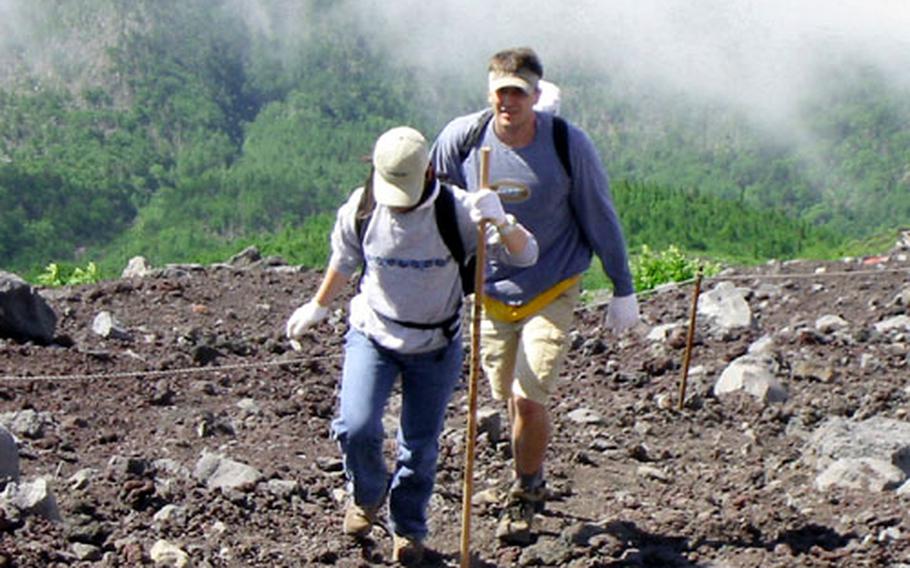 Climbers trek up Mount Fuji along Fuji Skyline Route at the height of about 8,000 feet. You do not see trees or grass above the fifth station.