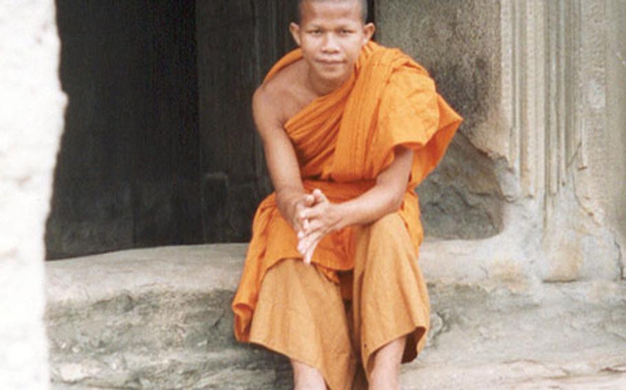 Meas, a 22-year-old Buddhist, sits on the steps on part of Angkor Wat.