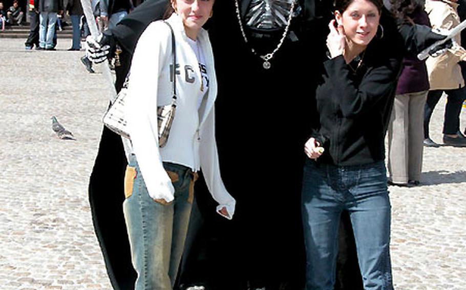 The Grim Reaper, looking ever-so-personable, poses with two fans.
