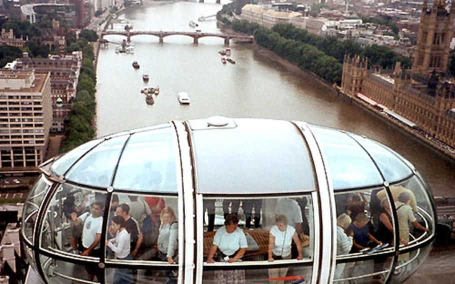 Passengers on the London Eye look out at the city as their observation capsule rises above the River Thames. In the background to the right are the Houses of Parliament and the tower of Big Ben.