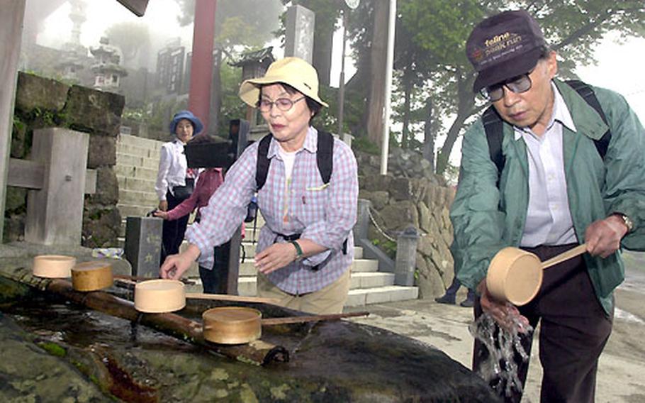 Japanese wash their hands in an act of purification before entering the shrine on Mount Mitake.