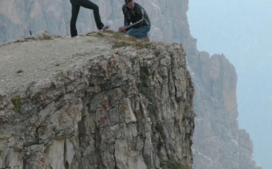 A couple finds a creative spot to pose for pictures atop a mountain at Passo Falzarego, near Cortina, northern Italy.