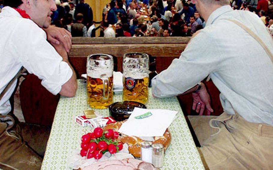 Men in traditional Lederhosen enjoy beer, food and the view at the Paulaner tent at last year&#39;s Oktoberfest.