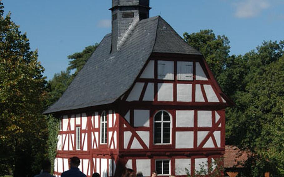 Visitors walk though the Hessenpark open-air museum past the half-timbered church from Niederhörlen. The Hessenpark features historical buildings from the German state of Hesse that were once in disrepair, then restored and rebuilt here.