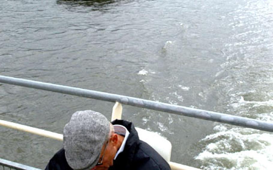 A passenger aboard the MS Berlin studies a guidebook as the ship passes a tanker working on the river. The Rhine is one of the busiest rivers in the world.