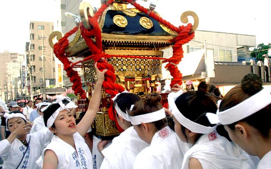 The women’s mikoshi is carried at the grand festival of Susanoo Shrine in Minami Senju, Tokyo, in June 2002. The women shoulder the portable shrine on two sticks, with no side sticks for added support. This allows for shaking of the shrine that is performed once every three years. The next full festival will be in 2005.