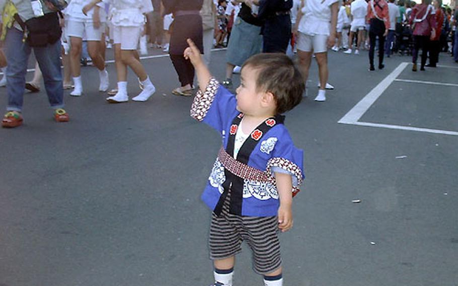 A young spectator takes in the sights and sounds of a mikoshi parade.