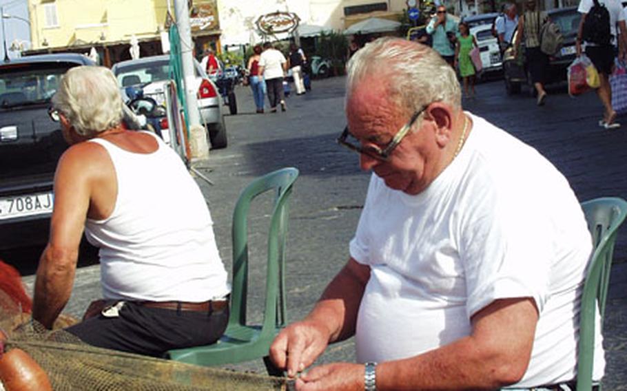 Fishermen mend their nets on the water’s edge at the Porto Marina Grande on Procida.