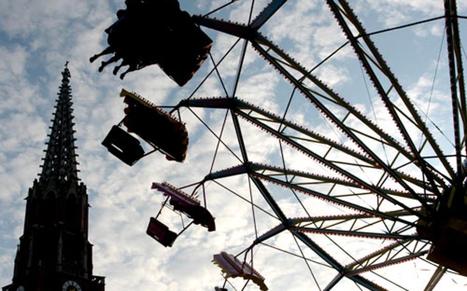 Visitors to the Auer Dult fly through the Munich sky on an amusement ride in front of the Mariahilfs church. The history of the Dult goes back to the 14th century, and it has been held on the Mariahilfsplatz in Au since 1905.