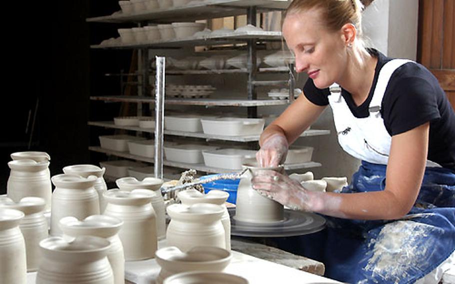 With her hands and the spinning potter’s wheel, a potter shapes a pitcher in a workshop in Soufflenheim.