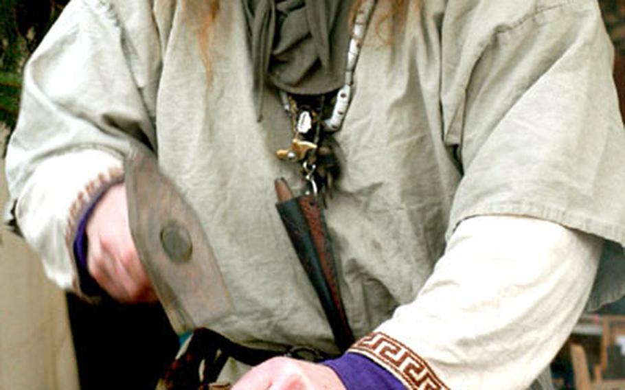 A blacksmith works at his anvil at the market, where you can buy swords, suits of armor and medieval clothing.