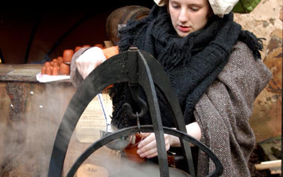 A young woman in medieval garb serves hot wine at the market at Ronneburg castle.