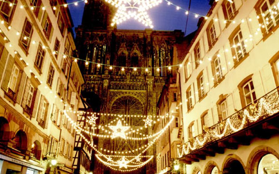 Fairy-light stars adorn the Rue Mercière, which leads toward the illuminated west facade of the Gothic cathedral at the Christmas market in Strasbourg, France.