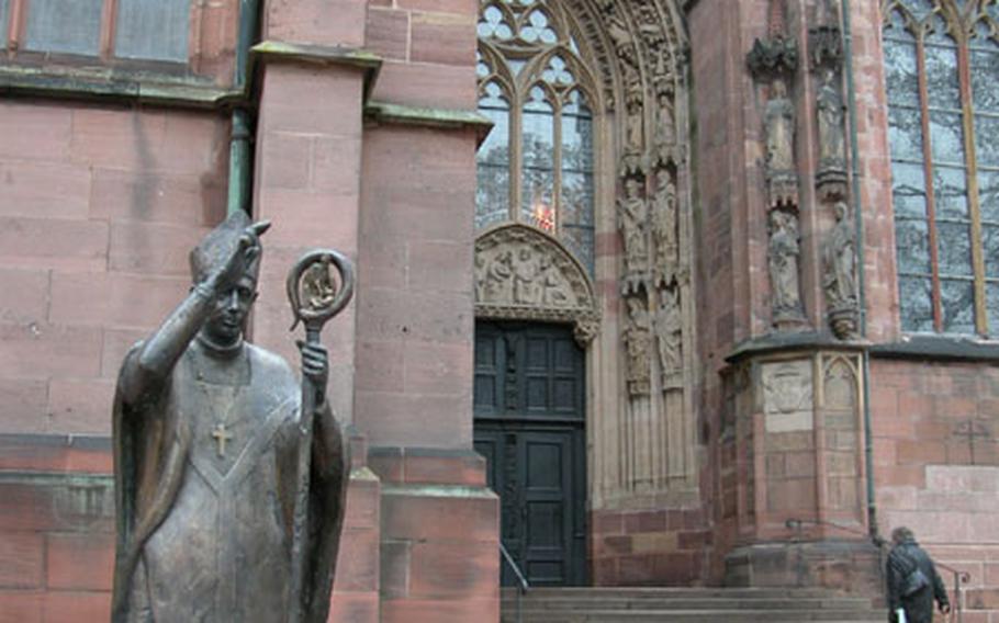 A statue of Bishop Burchard, an 11th-century bishop, stands outside the main entrance to the Worms cathedral, which features elaborate carvings depicting characters and scenes from the Bible.