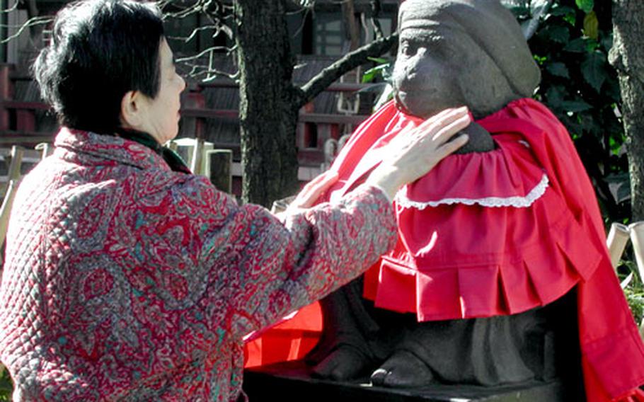 A lady touches a statue of a baby monkey held in a mother monkey’s arms at Hie Shrine.