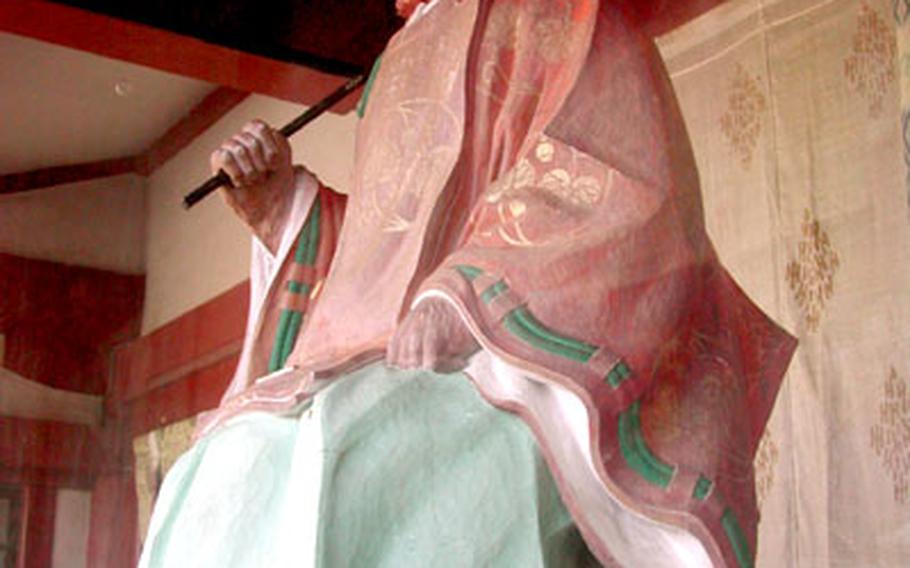 A statue of a female monkey sits on shelves on the legs of the gate arches on the left of the temple. A male statue sits on the right.