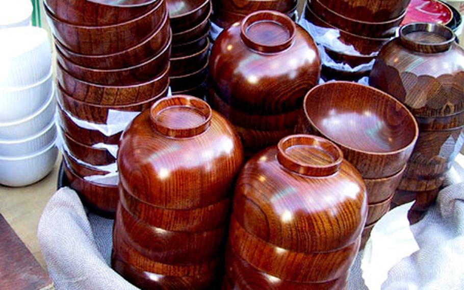 Stacks of polished wooden bowls, for soup or salad, were sold at the large December Boro-ichi flea market in Tokyo. The lacquered wooden bowls are a traditional Japanese art form — but because plastic imitations can be difficult to detect, this merchant had a bowl which had been vertically sawed in half to demonstrate it was the more desirable wood.