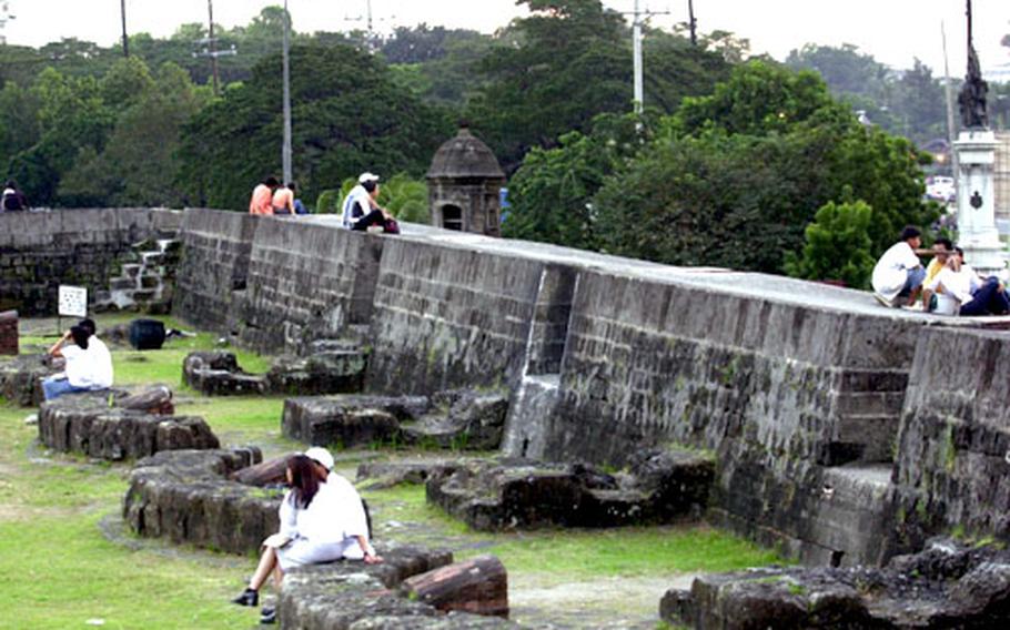 Along the walls of Intramuros in old Manila, couples relax and enjoy the warm evening.