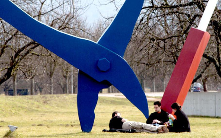 Visitors to the Vitra Design Museum rest under a giant sculpture by American artist Claas Oldenburg.