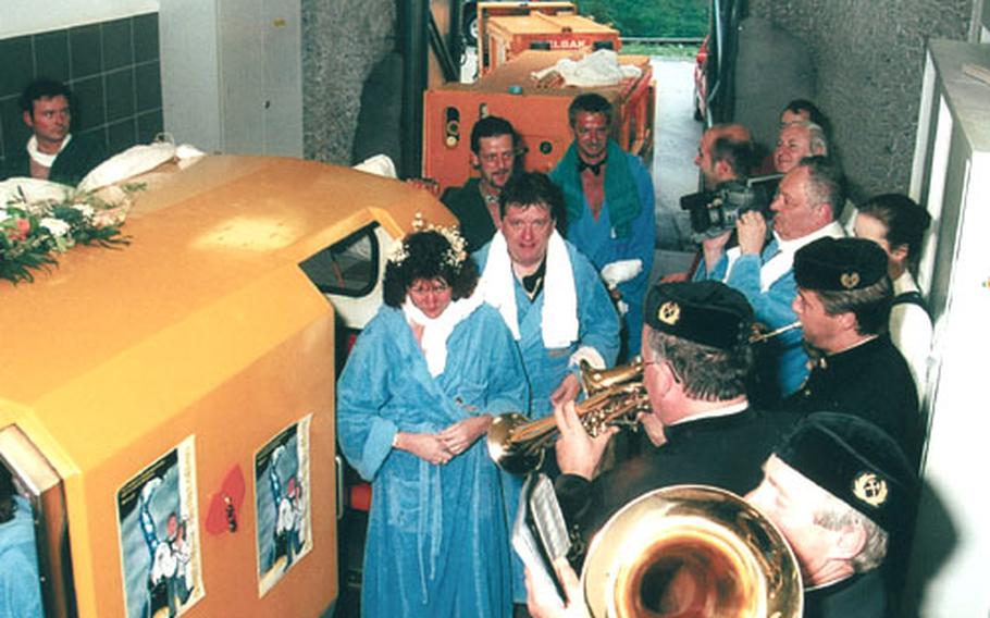 A small band and family members with video cameras accompany customers taking the radon treatment as they wait to board the little yellow train that takes them into the caves.