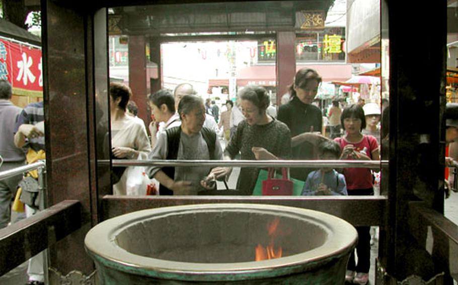 People stand to call in incense smoke to the places in their bodies where they have problems or illness. It is believed the incense smoke will cure the malady.