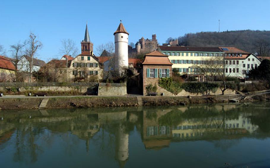 The old town of Wertheim is reflected in the water of the Tauber river. The city is located where the Tauber flows into the Main. The Kitsteinturm, or tower, is at center, with the steeple of the Stiftskirche at left, and the castle towering over the city in the background at right.