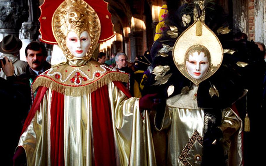 A pair of costumed revelers parade under the arcades of the Doges palace in Venice in 1995.