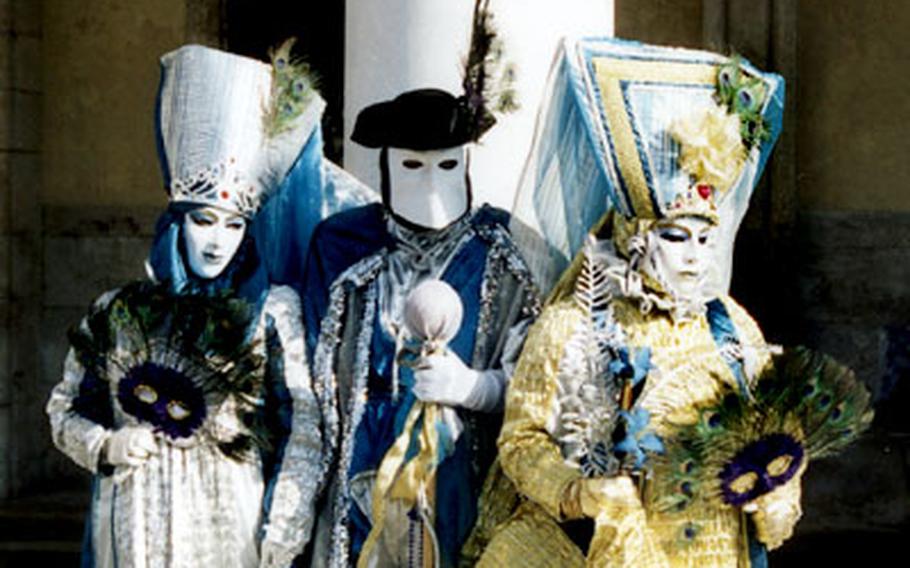 Three costumed Carnevale revelers, including the man in the center wearing a traditional Bauta mask, pose in front of Venice’s Doge Palace.