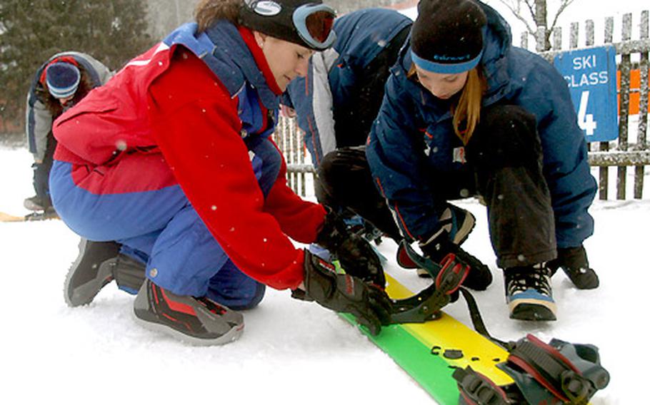 Patricia Joy, a snowboarding instructor at the Hausberg Lodge in Garmisch, Germany, helps Samantha Voltoline, 13, put on her snowboard for the first time during an instruction class. Joy had Voltoline begin on the snowboard on level ground and with only one foot in the bindings.