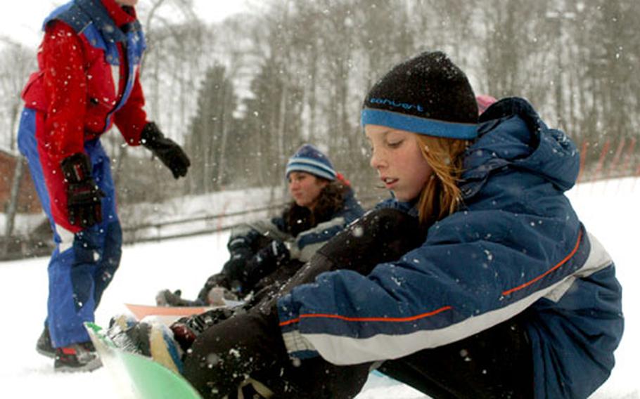 Samantha Voltoline, foreground, tries to figure out how to properly secure her snowboarding boots onto her snowboard. Voltoline took her first snowboarding class while her parents were taking advantage of the Operation R&R package from Iraq. In the background, Patricia Joy finishes helping Samantha’s sister, Jade, 14. Both sisters took the snowboarding class.