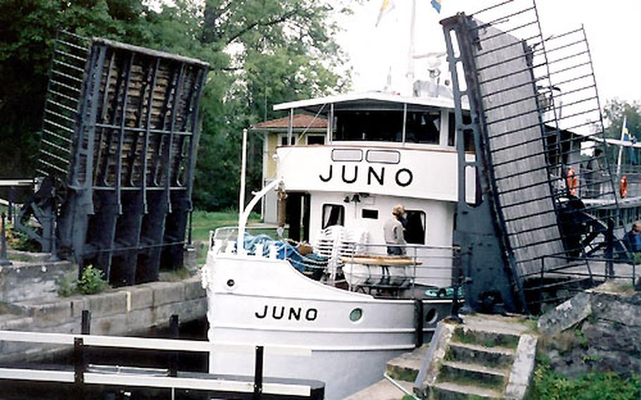 The M/S Juno passes through a lock and past a country road bridge. The canal boats move at 5 mph, so it is possible for passengers to disembark, move ahead and take a photo of the boat as it approaches.