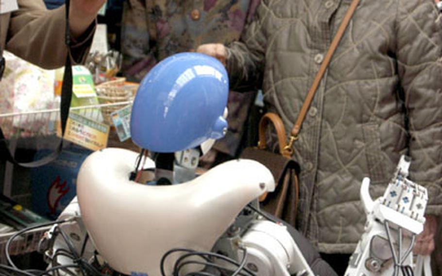 Women in Kitakyushu watch the robot TMSUK on its first adventure into a public space near Fukuoka, Japan.