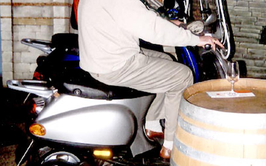 Visitors sit on Vespa scooters and listen through headphones to an explanation about wines of the Chianti region. It is one of the more novel rides at Vinopolis.