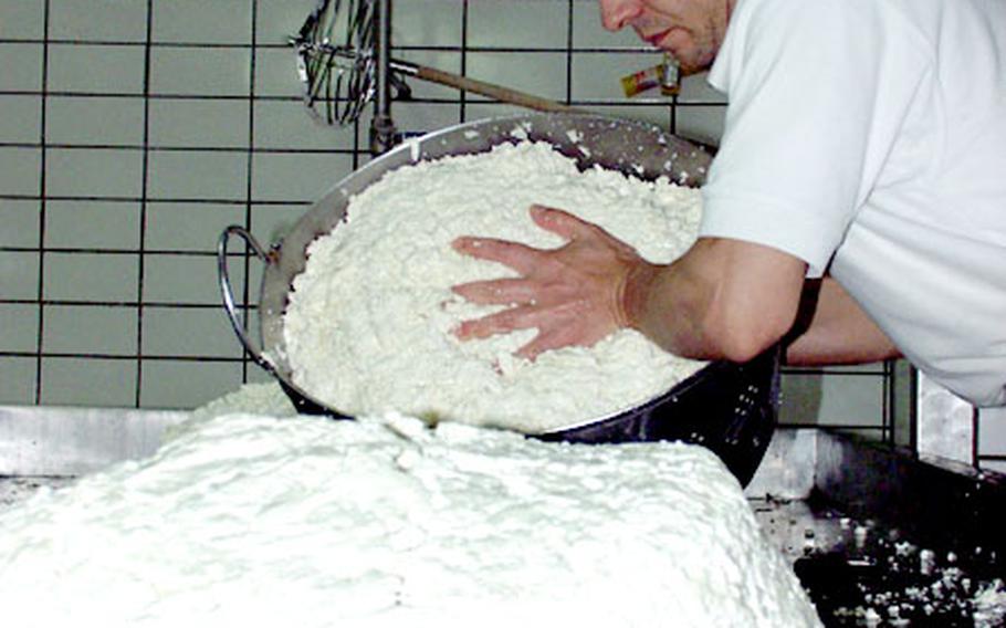 An employee of Schiavone Caseificio separates curdled milk to prepare to shred it through a grinder.