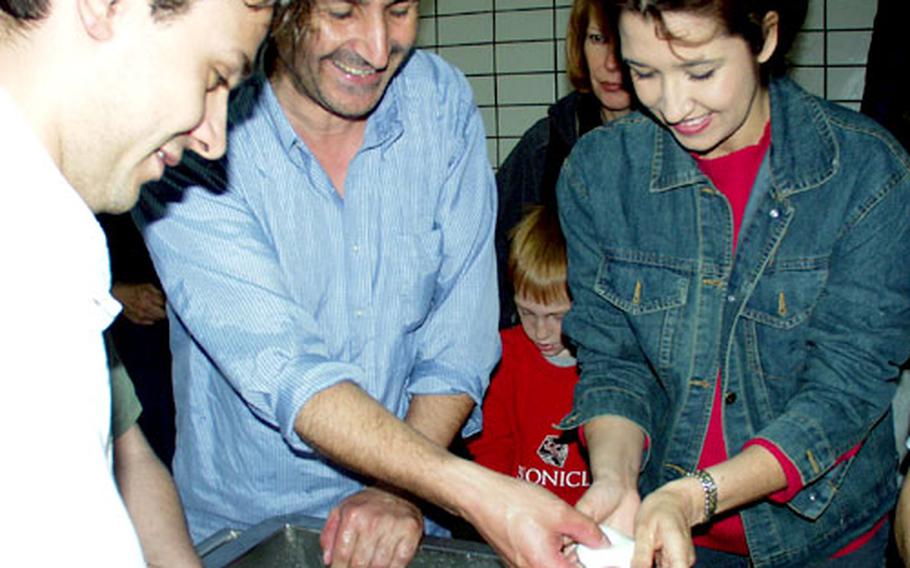 Bruno Schiavone, owner of the “caseificio,” or dairy, shows Stephanie Ortega how to stretch the buffalo mozzarella into balls during the final process of making the product.