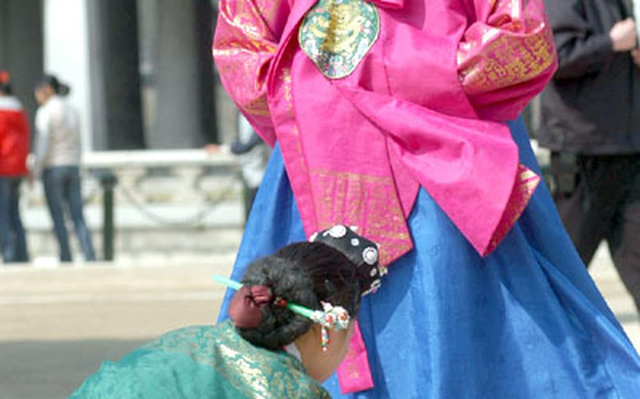 Two women try on hanboks, the traditional Korean dress, on the grounds of Gyeongbok Palace.