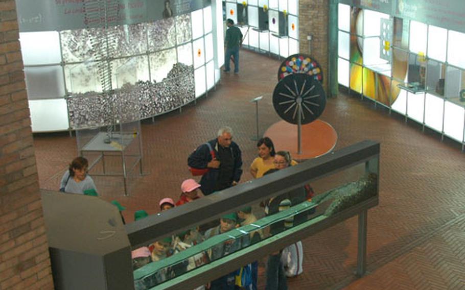 Visitors to the Naples Citta&#39; della Scienza center look at a display explaining wave formation and effects. Many of the displays require visitor interaction, including this one, which required people to push a button to start the waves.
