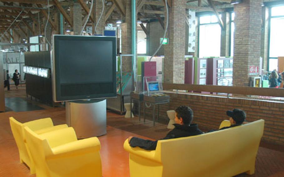 Visitors to the Citta&#39; della Scienza sit in front of a big-screen TV to watch a short presentation on communications in the center&#39;s "Signs, Symbols, Signals: Communicating Today" section.