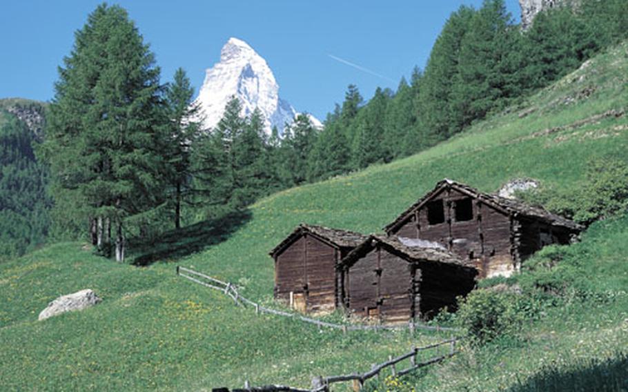 The tip of the 14,692-foot Matterhorn, still covered with snow in the summer, rises above the mountain slopes surrounding the resort of Zermatt in the canton of Valais.