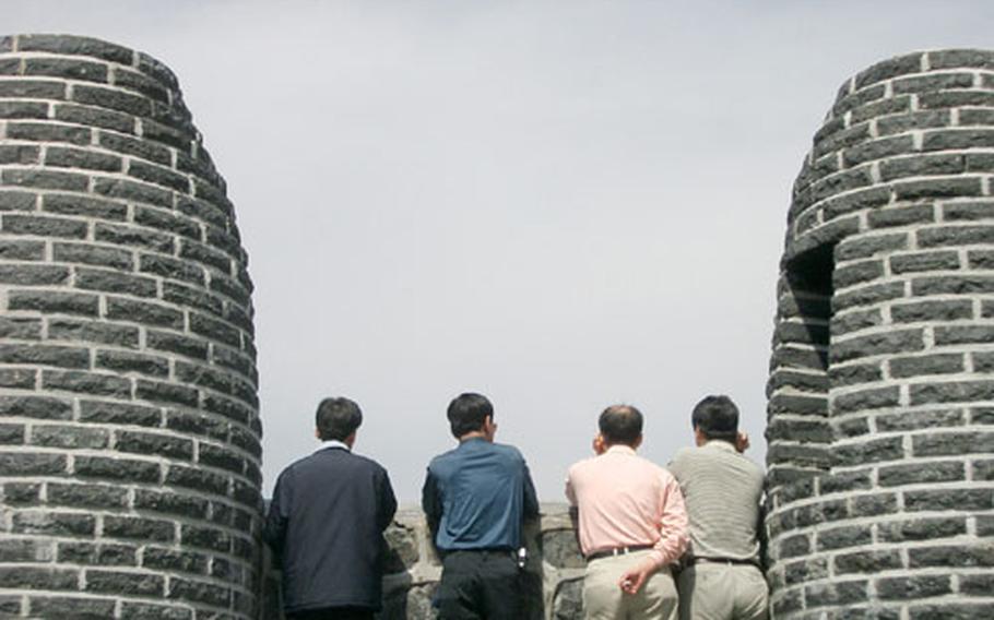 A group of men pause and check out the view from a series of huge brick ovens once used as signal fires to relay emergencies or border attacks from the outlands back to the capital, Seoul.