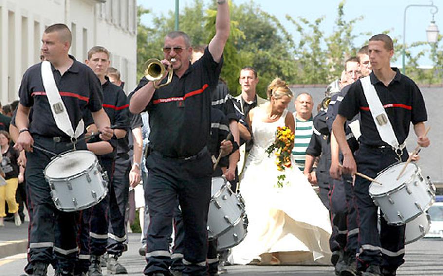 Firefighters escort a colleague and his bride through the streets of Bayeux.