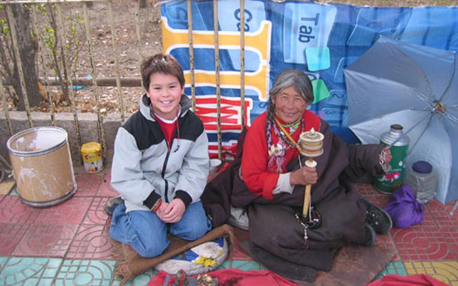 A kindly Tibetan woman selling souvenirs outside our hotel poses with the youngest Jorgenson.
