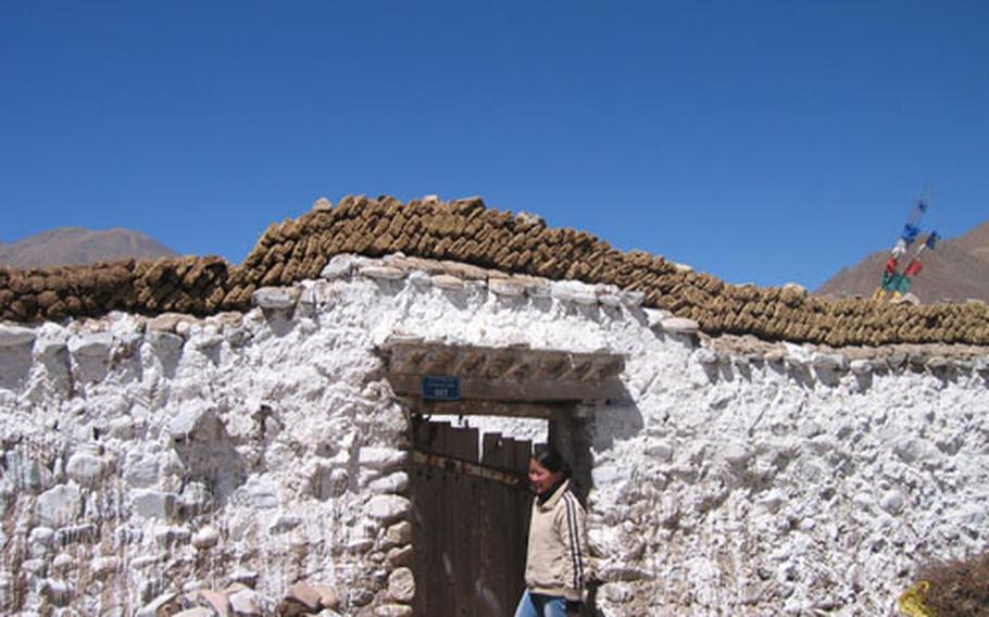 The Jorgenson tour guide, Yangqing, looks for someone at home. Animal dung cakes on the upper walls are drying in the sun and will be burned for heat.