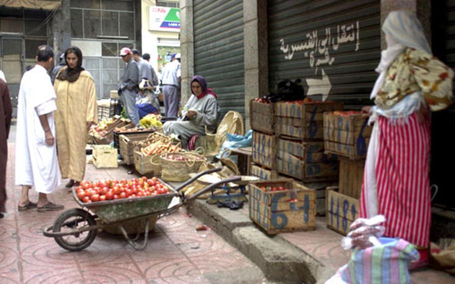 Women sell produce on the side of a downtown street in Tangier, Morocco. Spices of all kinds are found in shops and at market stands spread throughout the city.