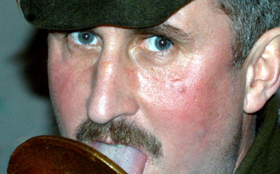 A local hunter demonstrates the finger-licking taste of his brew, the  sold at the Christmas market.