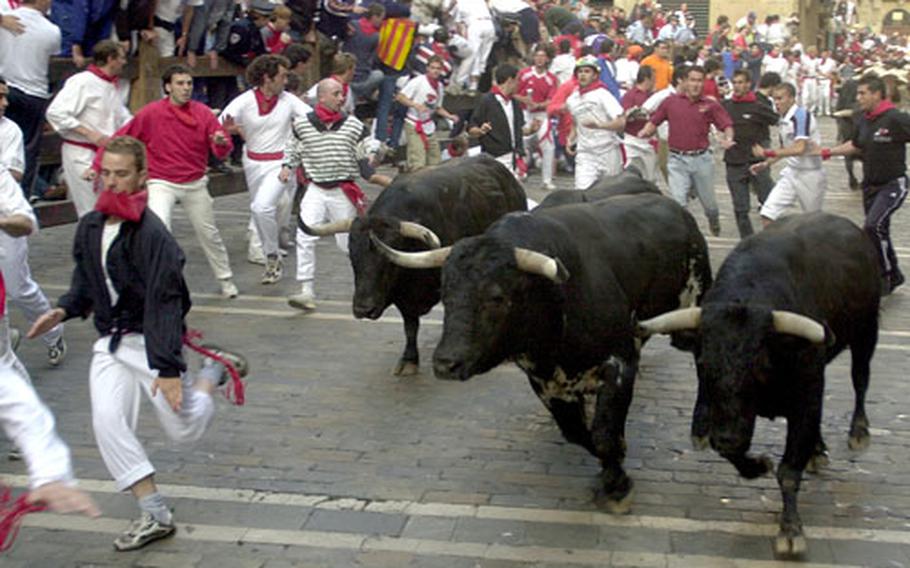Runners try to evade bulls charging through the streets during the annual Running of the Bulls at the San Fermin Fiesta in Pamplona, Spain.