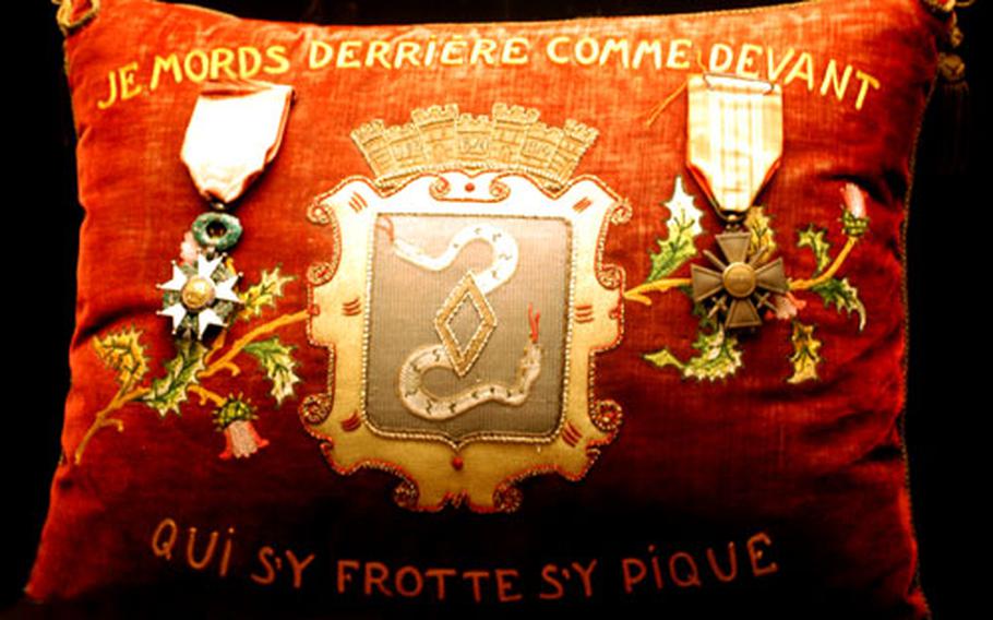 A decorative pillow in the museum shows the crest of Bitche with two war medals.